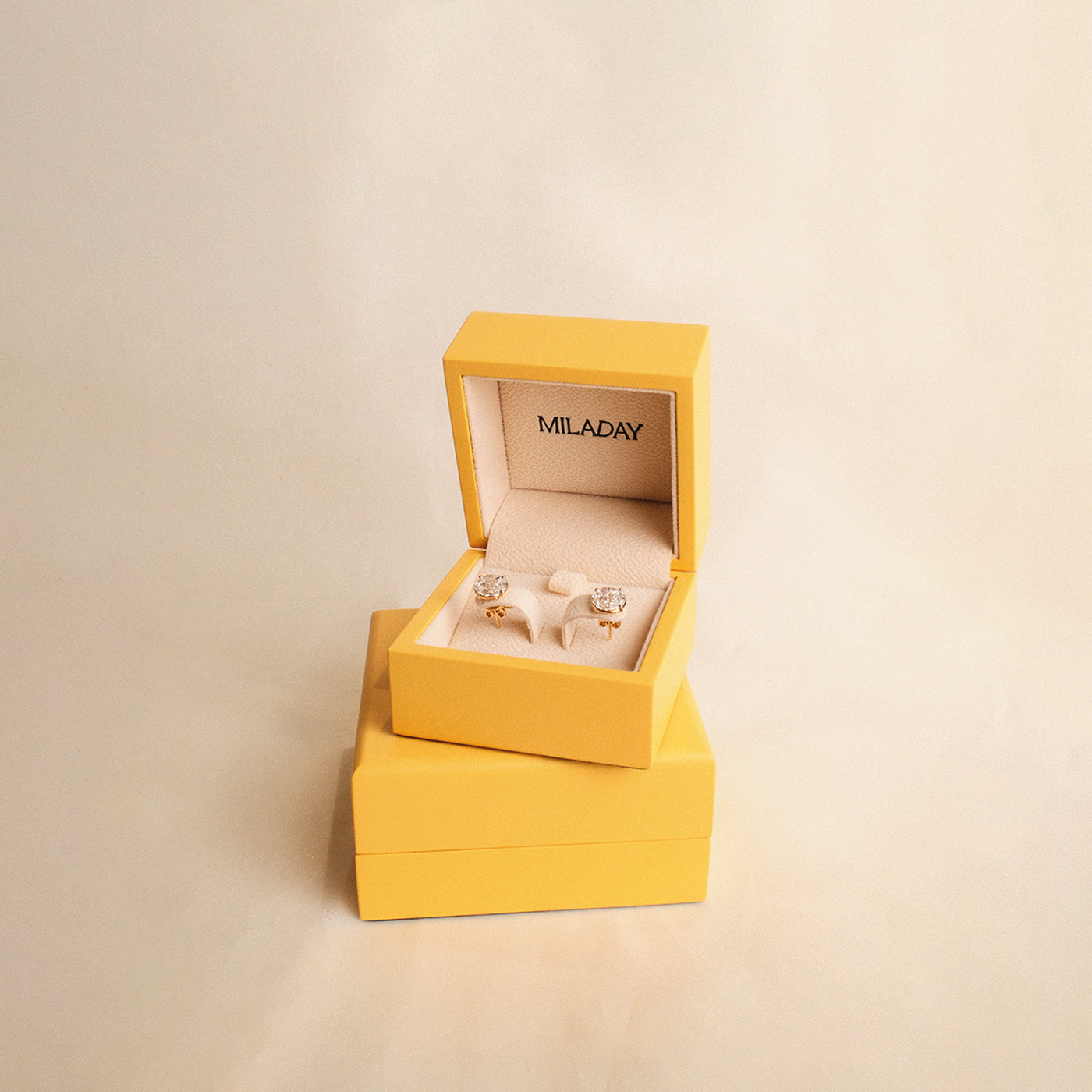 Yellow jewelry box with earrings on a beige background
